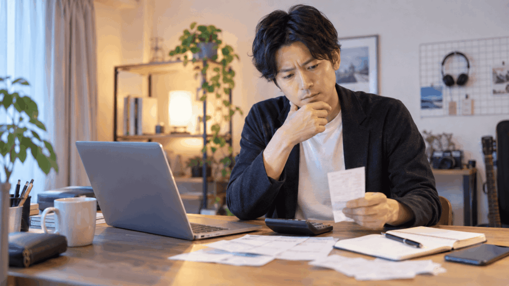 パソコンの前で領収書を確認する副業Webデザイナー